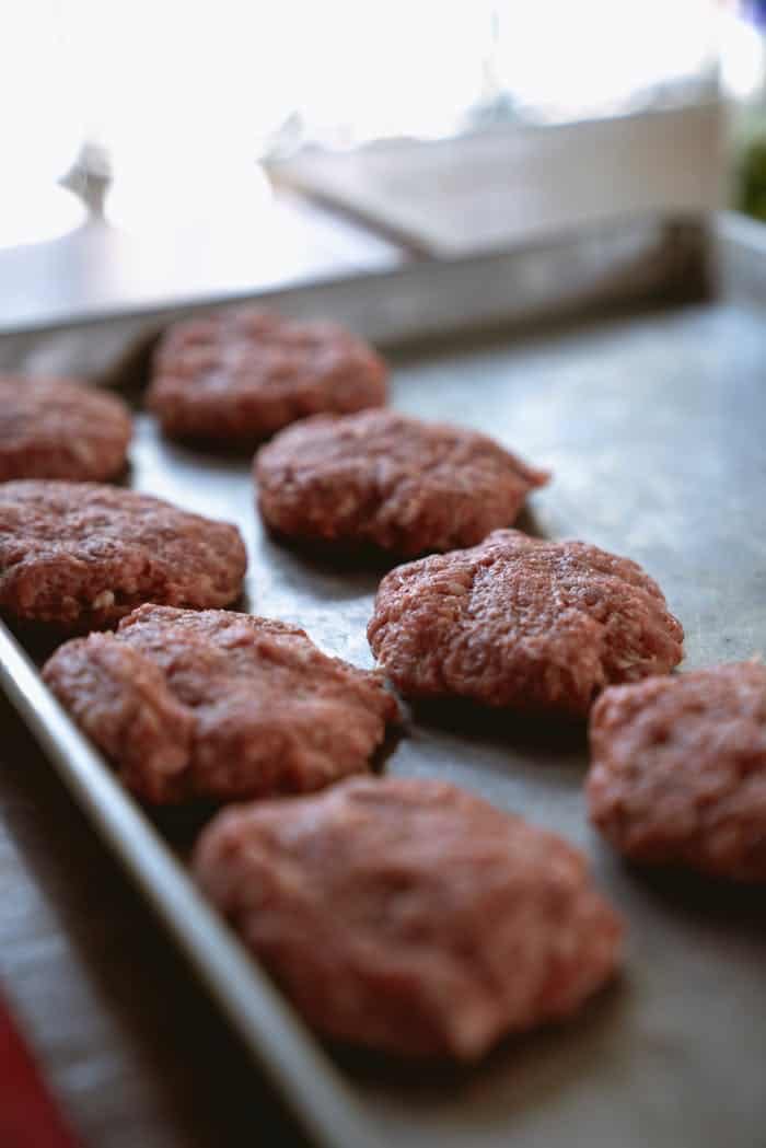 ours-journey Close-up of raw beef patties on a metal tray ready for cooking.