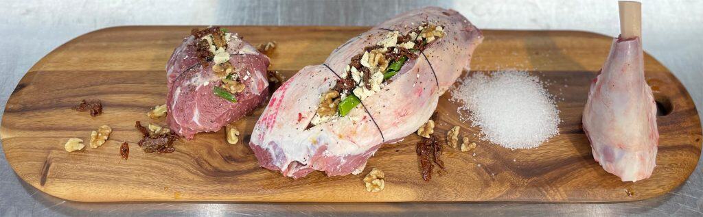 Premium Fussy Meats beef roasts with herbs and spices on wooden cutting board, perfect for grilling or roasting.